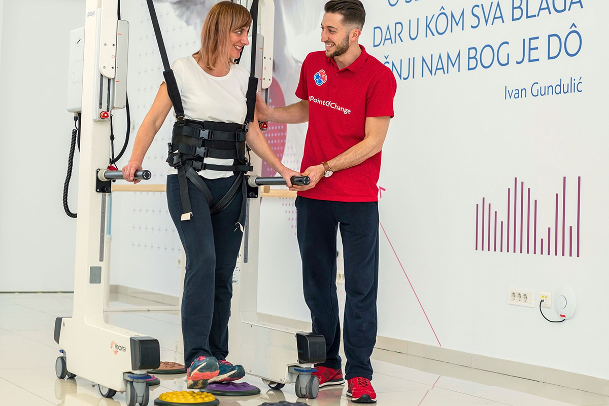 A woman practises walking with a support harness under a therapist’s supervision at Glavic Clinic.